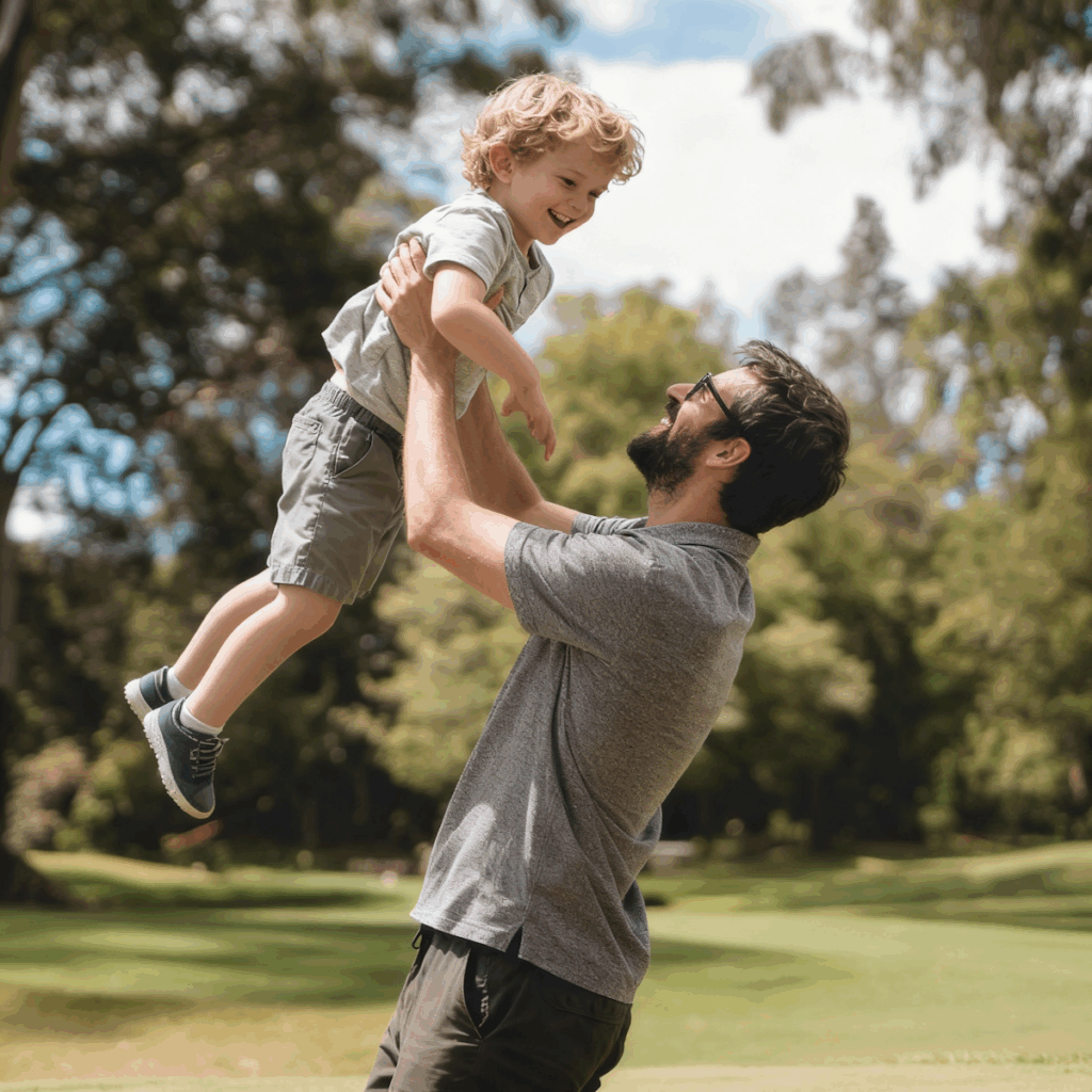 A joyful moment of a father lifting his smiling son in a sunny park, surrounded by lush greenery and a clear blue sky